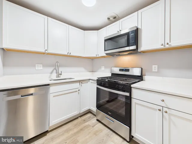 a kitchen with white cabinets stainless steel appliances and sink