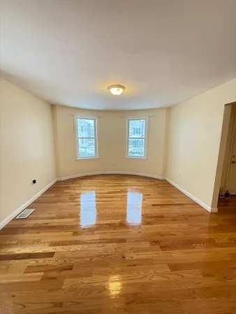 a view of empty room with wooden floor and window