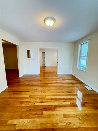 a view of an empty room with window and wooden floor