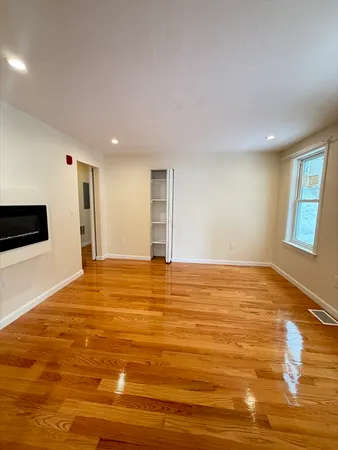 a view of an empty room with wooden floor and windows