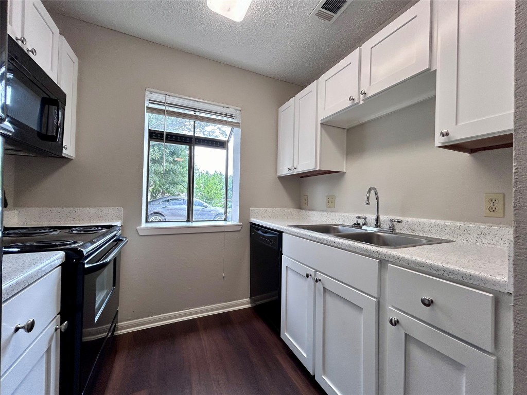 8905 Schick Road, Unit C Austin, TX 78729 - Photo 4 of 25 a kitchen with stainless steel appliances granite countertop white cabinets stove top oven and sink