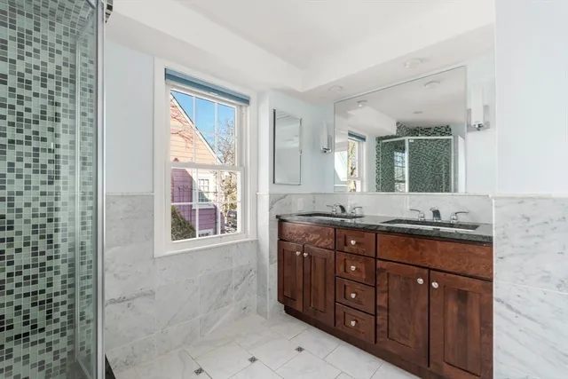 a bathroom with a granite countertop double vanity sink and mirror
