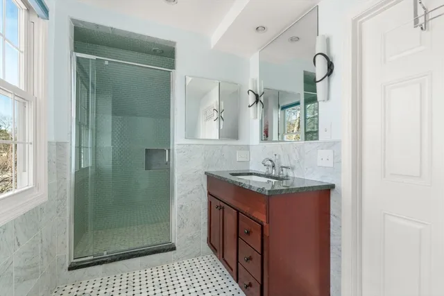 a bathroom with a granite countertop sink a mirror and shower