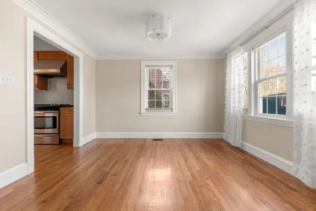 an empty room with wooden floor cabinet and windows