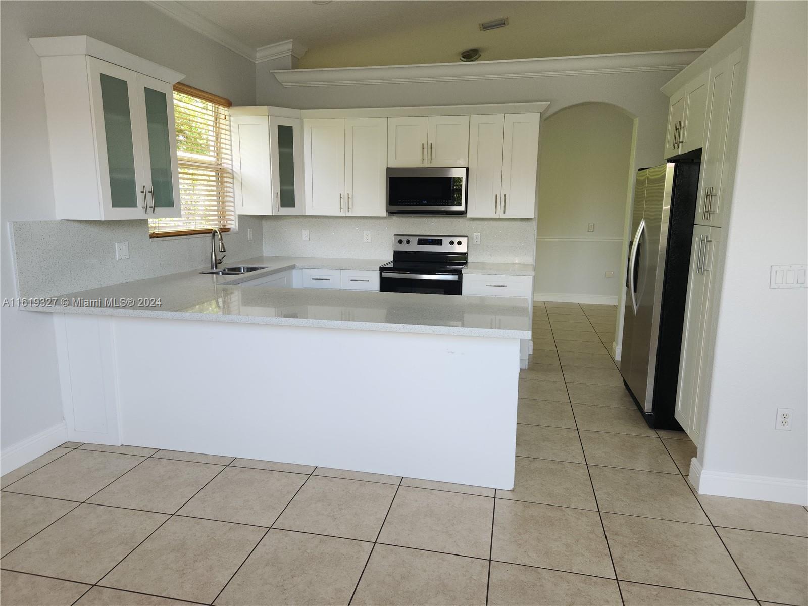 14201 Southwest 15th Street Miami, FL 33184 - Photo 3 of 37 a kitchen with stainless steel appliances a sink a microwave a refrigerator and a counter top space