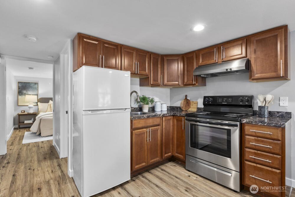 5926 34th Avenue Southwest Seattle, WA 98126 - Photo 20 of 36 a white refrigerator freezer sitting inside of a kitchen with stainless steel appliances granite countertop wooden cabinets and a stove top oven
