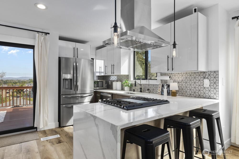 5926 34th Avenue Southwest Seattle, WA 98126 - Photo 6 of 36 a kitchen with stainless steel appliances granite countertop a table chairs and a refrigerator
