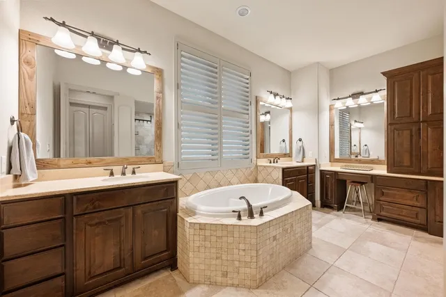 a bathroom with a tub double vanity sink and a large mirror