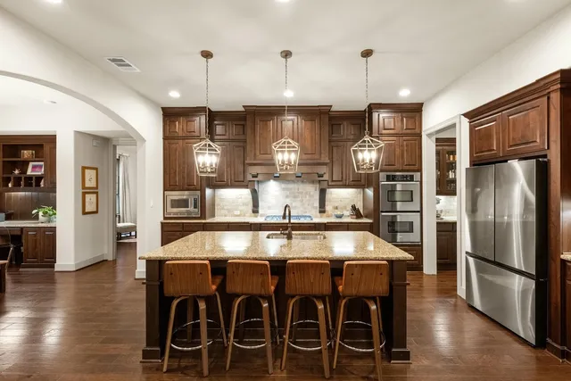 a kitchen with stainless steel appliances granite countertop a dining table chairs and granite counter tops