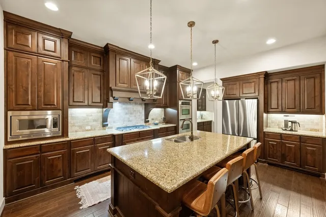 a kitchen with stainless steel appliances granite countertop a sink refrigerator and cabinets