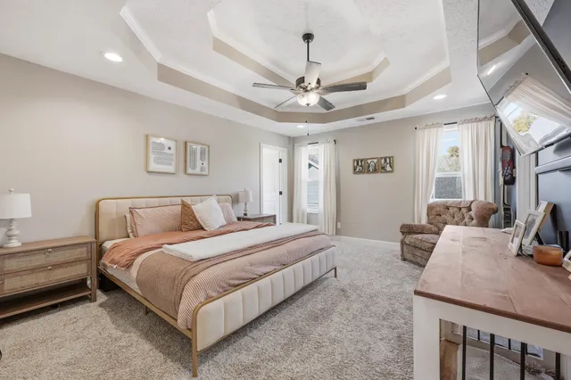 a spacious bedroom with a bed a chandelier and a desk