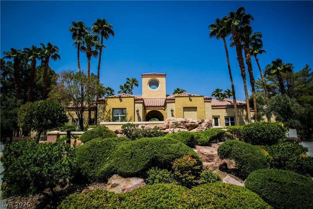 230 East Flamingo Road, Unit 122 Las Vegas, NV 89169 - Photo 1 of 7 A Mediterranean-style facade awaits, framed by tall palm trees and lush, manicured landscaping.