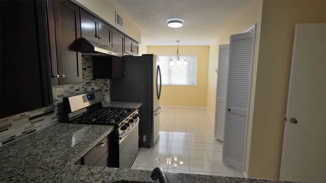 a kitchen with stainless steel appliances granite countertop a refrigerator and a stove
