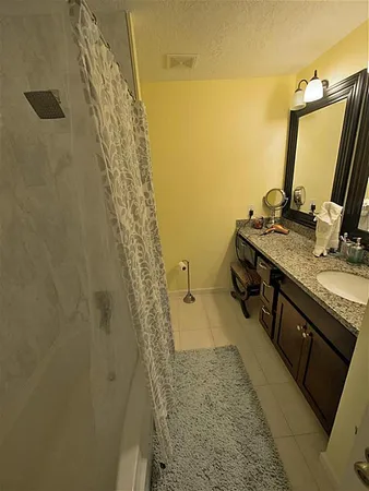 a bathroom with a granite countertop sink a mirror and shower