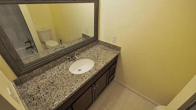 a bathroom with a granite countertop sink and a mirror