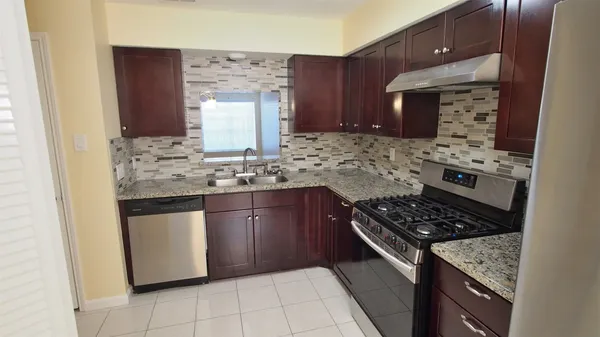 a kitchen with stainless steel appliances granite countertop a stove a sink and a microwave