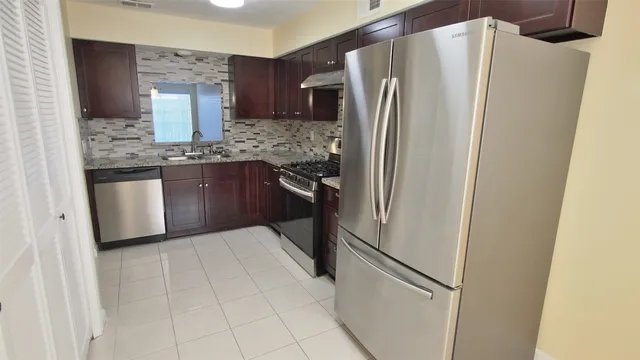 a kitchen with stainless steel appliances granite countertop a refrigerator and a sink