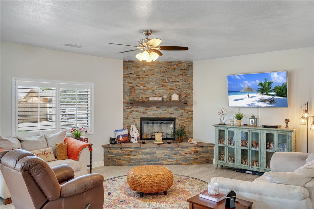 13178 Setancket Road Apple Valley, CA 92308 - Photo 8 of 24 a living room with furniture a fireplace and a flat screen tv