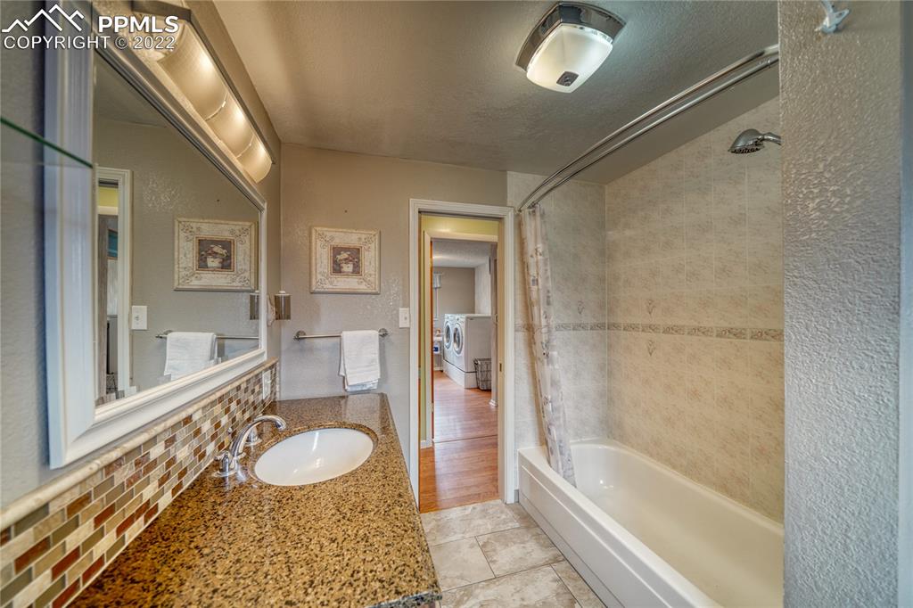 7035 Chippewa Road Colorado Springs, CO 80915 - Photo 12 of 22 a bathroom with a granite countertop sink a mirror and a shower