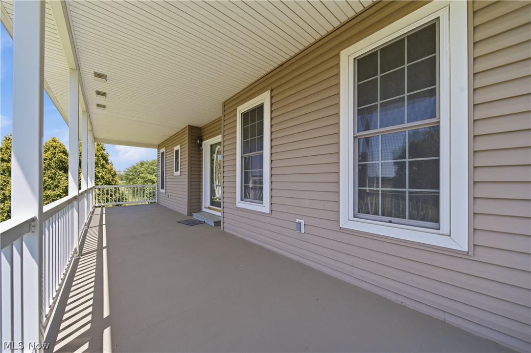 12159 Lawndell Road Southwest Beach City, OH 44608 - Photo 4 of 49 Expansive covered porch featuring a painted concrete surface, white railing system, and vinyl siding exterior