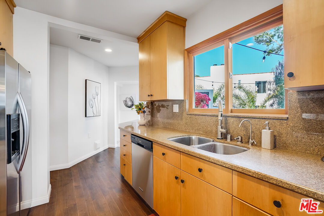 8912 Appian Way Los Angeles, CA 90046 - Photo 20 of 55 a kitchen with stainless steel appliances granite countertop a sink a refrigerator and a wooden floor