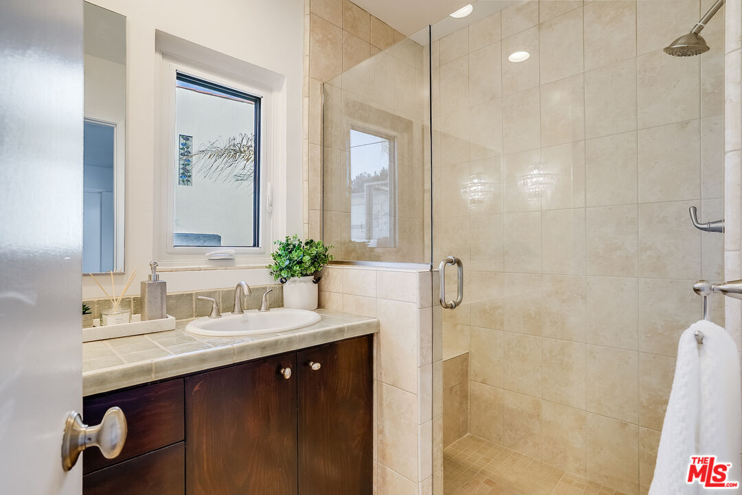 8912 Appian Way Los Angeles, CA 90046 - Photo 24 of 55 a bathroom with a double vanity sink a mirror a shower and a bathtub