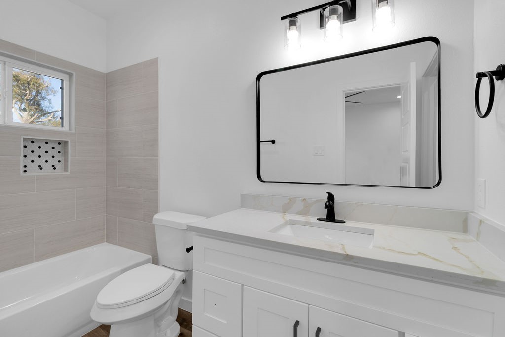 104 Runnels Street Willis, TX 77378 - Photo 22 of 27 a bathroom with a toilet sink vanity tub and mirror