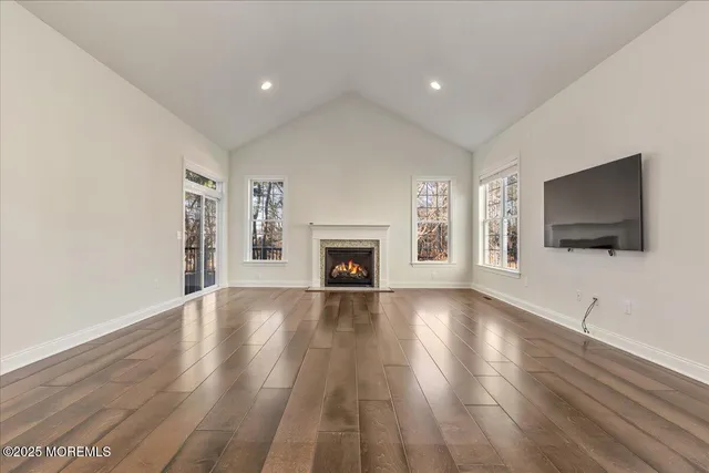 a view of an empty room with wooden floor fireplace and a window