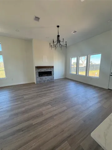 an empty room with wooden floor fireplace and windows