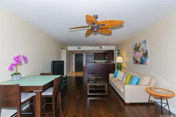 a living room with furniture kitchen view and a wooden floor