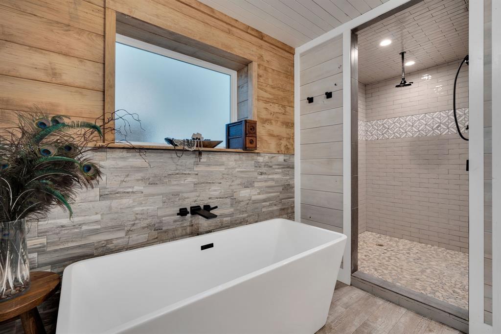 930 Pigg Road Waxahachie, TX 75165 - Photo 20 of 40 Freestanding soaking tub with wall-mounted matte black faucet, surrounded by wood paneling and stone-look tile