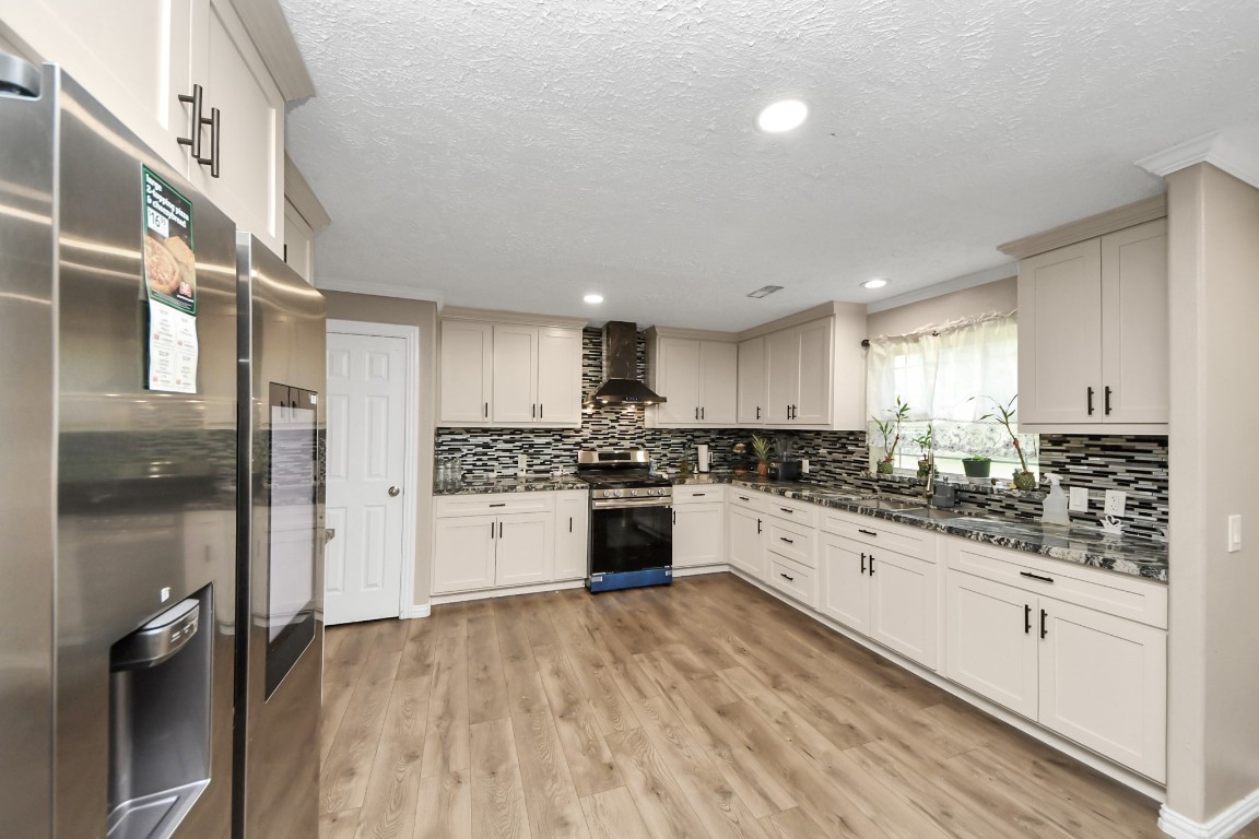 11844 Padok Road Houston, TX 77044 - Photo 18 of 41 a large kitchen with a refrigerator a sink dishwasher a stove and white cabinets with wooden floor