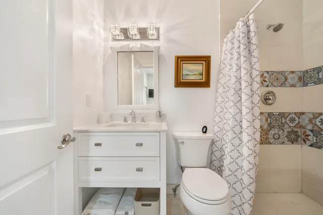 a bathroom with a granite countertop toilet a sink and a mirror