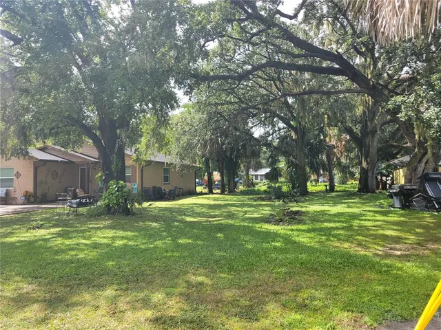 a view of a house with a big yard and large trees