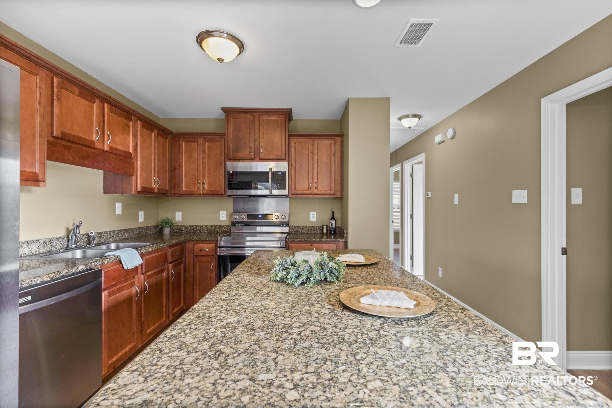 2084 Redpine Drive Semmes, AL 36575 - Photo 9 of 22 Kitchen with stainless steel appliances, dark stone countertops, and brown cabinets