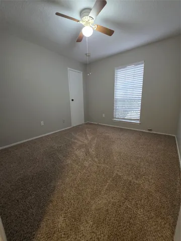an empty room with windows and fan chandelier fan
