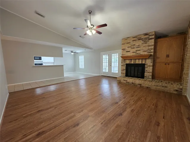 an empty room with wooden floor fireplace and windows