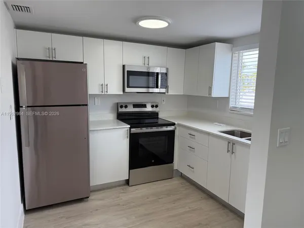 a kitchen with a refrigerator stove and white cabinets