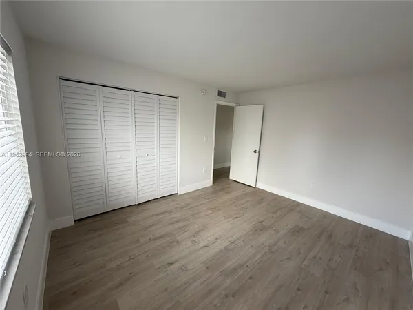 an empty room with wooden floor and windows with curtains