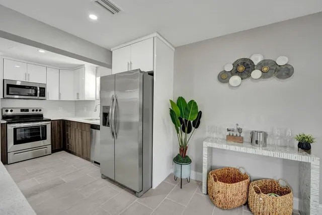 a kitchen with stainless steel appliances granite countertop a refrigerator a stove a sink dishwasher and white cabinets with wooden floor