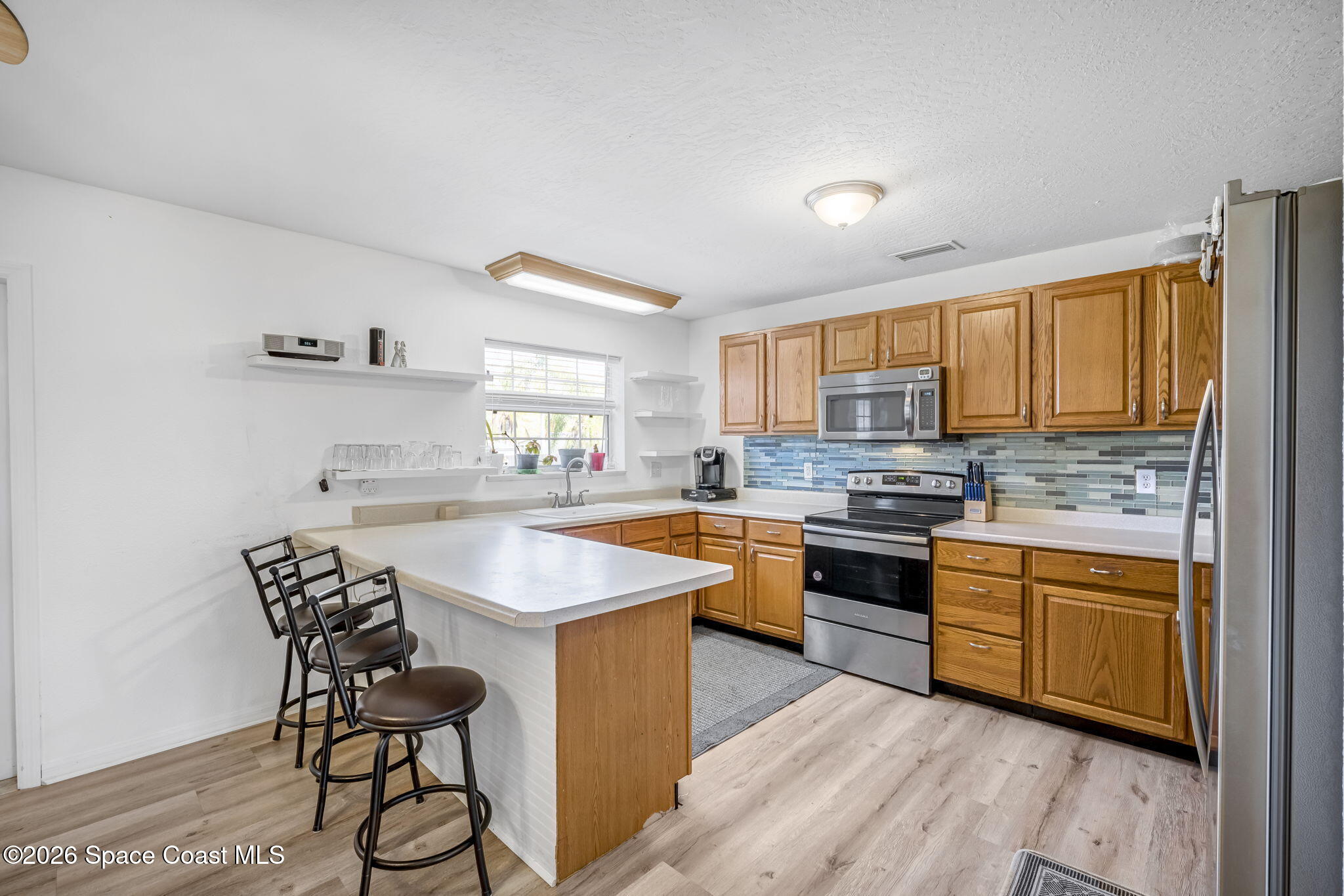3404 Kilbee Street Mims, FL 32754 - Photo 10 of 30 a kitchen with stainless steel appliances granite countertop wooden cabinets a sink a stove a refrigerator and island with wooden floor