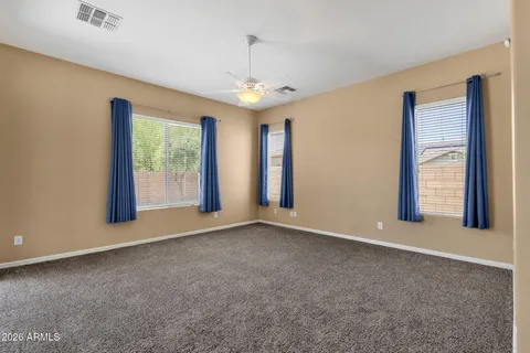 an empty room with windows and chandelier fan