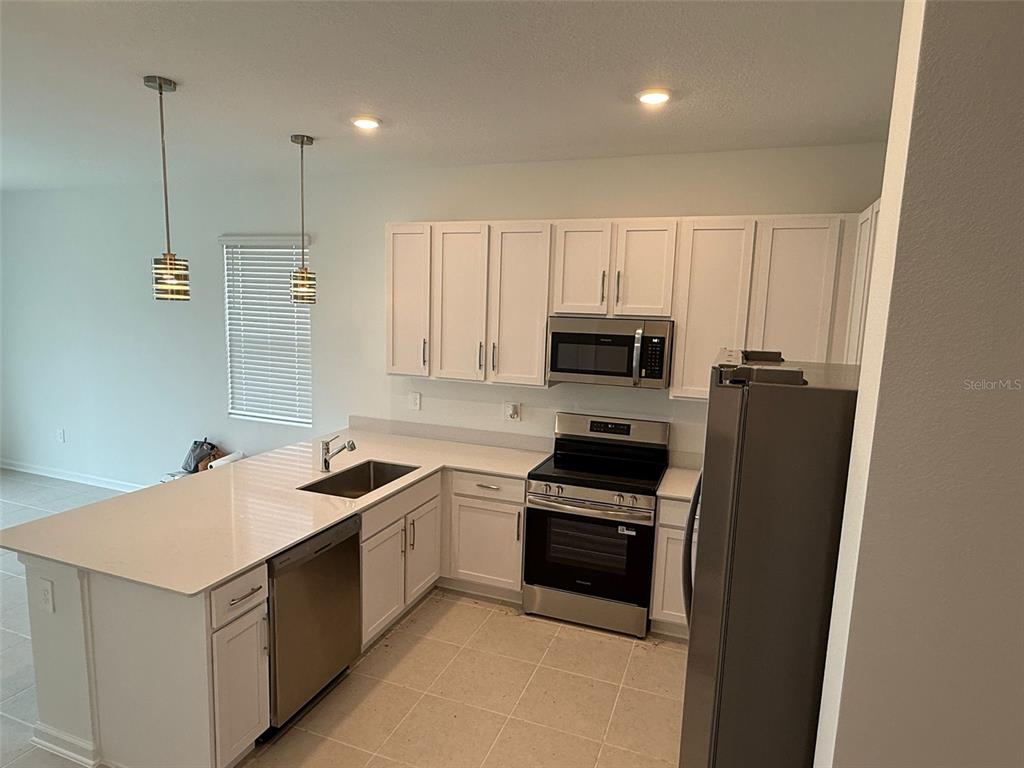 2691 Skyline Loop Kissimmee, FL 34758 - Photo 5 of 27 a kitchen with stainless steel appliances granite countertop a sink a stove a refrigerator and cabinets