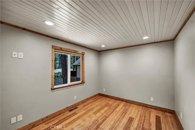 a view of empty room with window and wooden floor