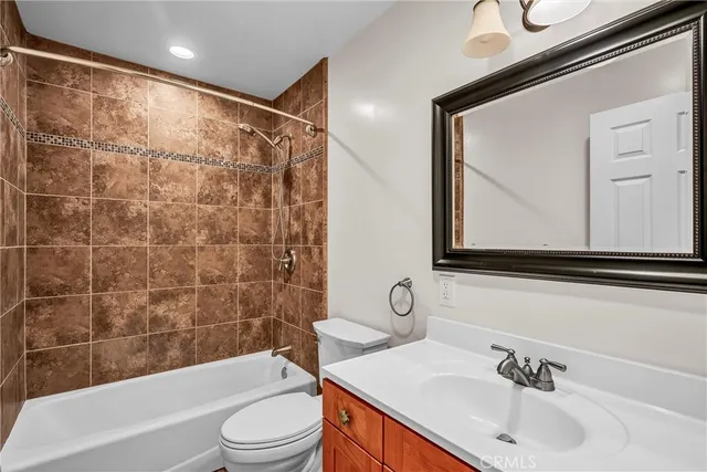 a bathroom with a bathtub shower sink vanity mirror and toilet
