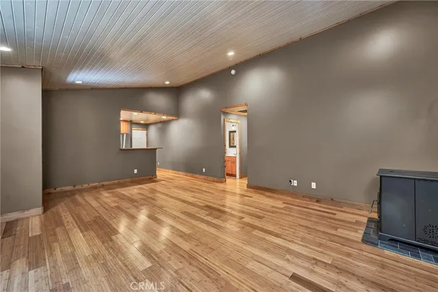 a view of an empty room with wooden floor and a ceiling fan