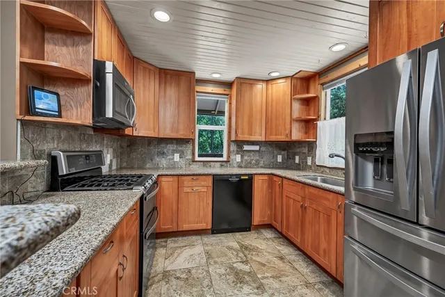 a kitchen with stainless steel appliances granite countertop a stove sink refrigerator and cabinets