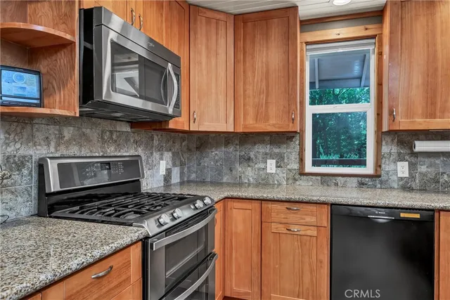 a kitchen with granite countertop wooden cabinets stainless steel appliances and a counter space