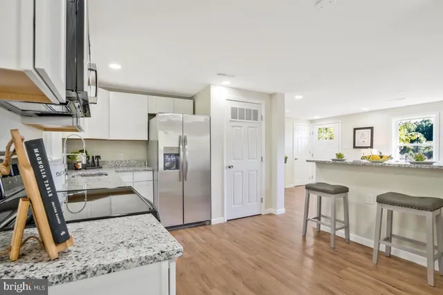 a kitchen with granite countertop a refrigerator stove and wooden floor