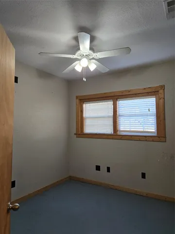 an empty room with a window and a ceiling fan